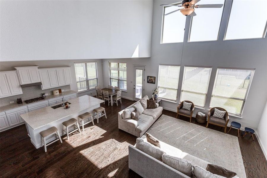 Living room featuring a high ceiling, ceiling fan and wood floors