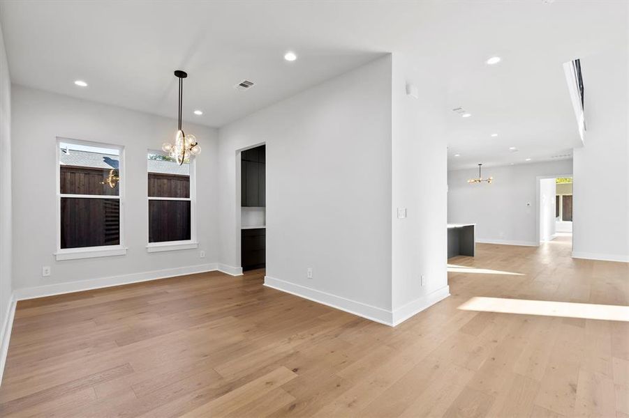 Unfurnished room featuring light hardwood / wood-style floors and a notable chandelier