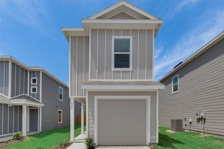 View of front of home featuring a garage, a front yard, and central AC unit