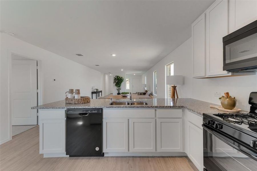 Kitchen featuring black appliances, light hardwood / wood-style floors, and white cabinets