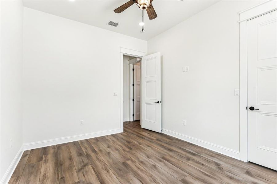 Bedroom 3 with ceiling fan, light hardwood type flooring, and walk in closet