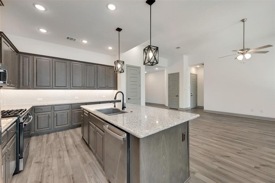 Kitchen with ceiling fan, sink, a center island with sink, stainless steel appliances, and light wood-type flooring