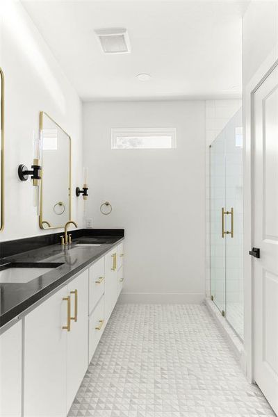 Bathroom featuring tile floors, a shower with shower door, and dual bowl vanity
