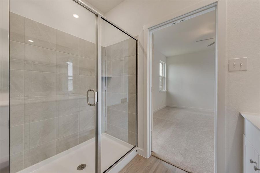 Bathroom featuring wood-type flooring, a shower with door, vanity, and ceiling fan