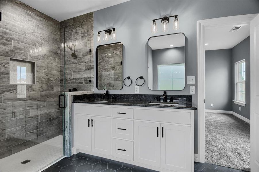 Bathroom with a shower with shower door, tile flooring, oversized vanity, and dual sinks