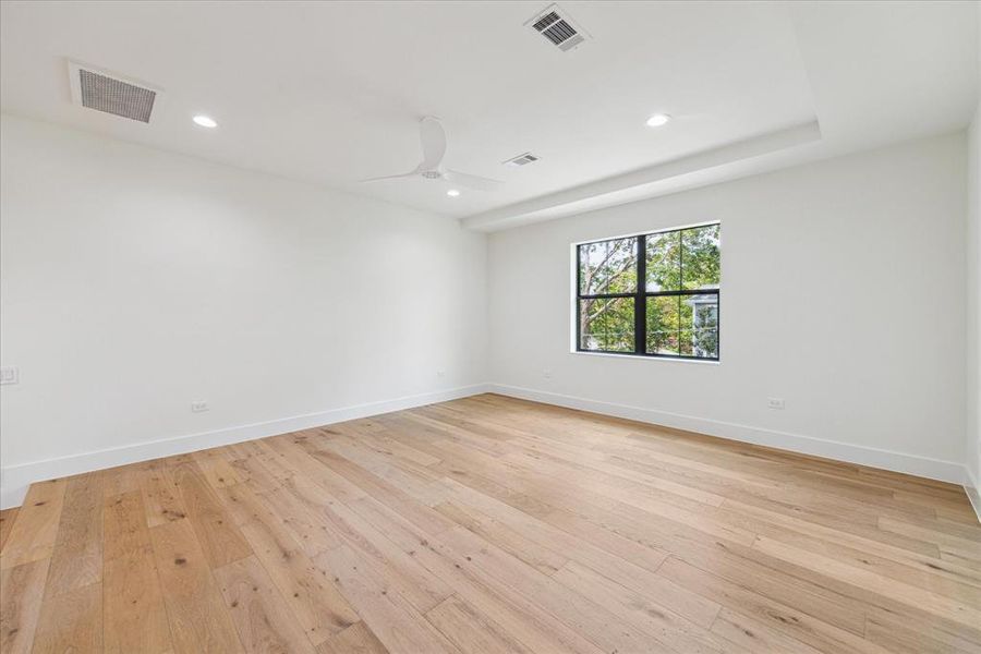 The alternate view of the game room showcases tray ceilings and a stylish ceiling fan, adding to the room’s elegance. Large windows offer expansive views overlooking the backyard, enhancing the space's connection to the outdoor environment.