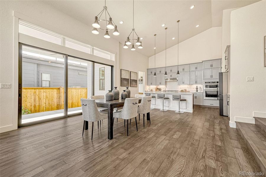 The dining room is right off of the living room and kitchen. Plenty of space, soaring high ceilings, custom, smart lighting and luxury vinyl plank flooring.