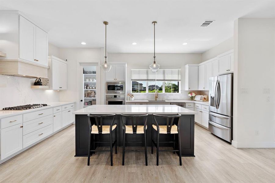 Charming kitchen with stainless-steel appliances, custom venting, and elegant floating shelves.