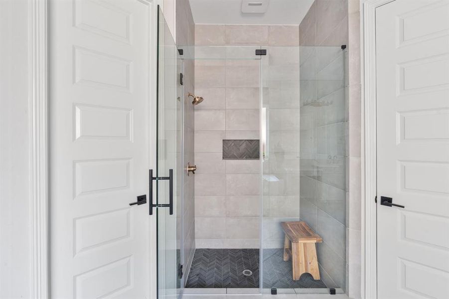 The primary bathroom also has a walk-in shower with tile surround, tile floors, and glass door.