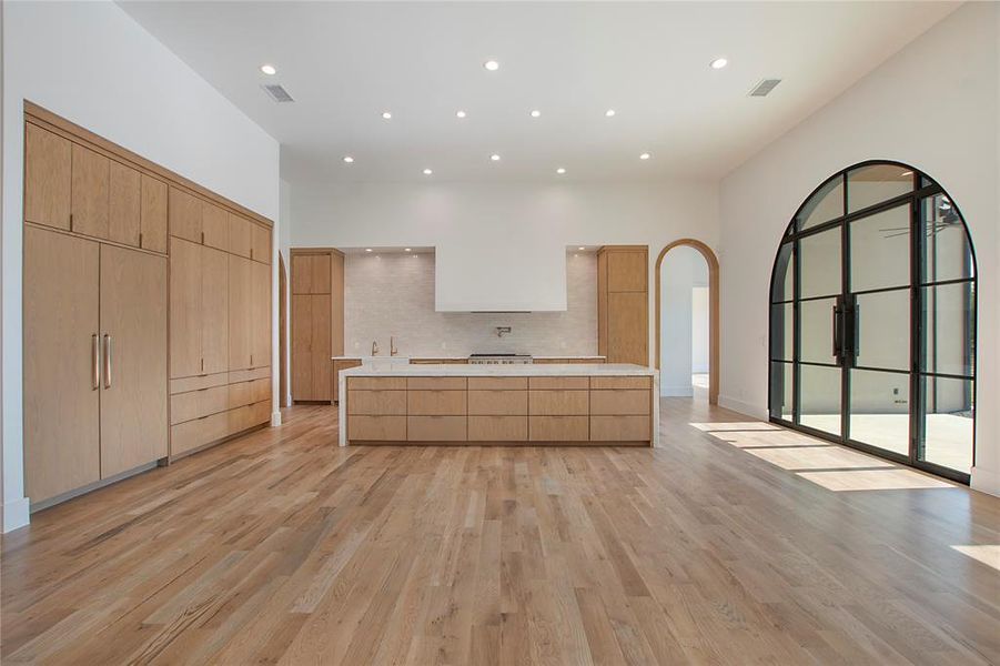 Kitchen with sink, a center island, light hardwood / wood-style floors, and backsplash