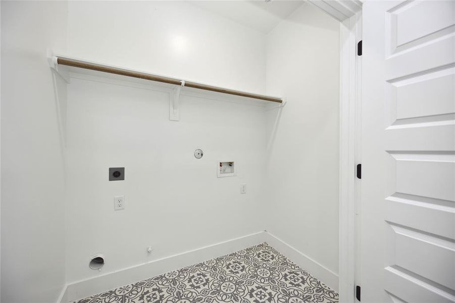 The oversized laundry room features patterned tile flooring and built-in shelving, making laundry day a breeze!