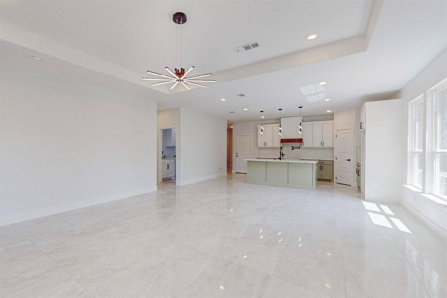 Unfurnished living room featuring sink, light tile patterned flooring, and a chandelier