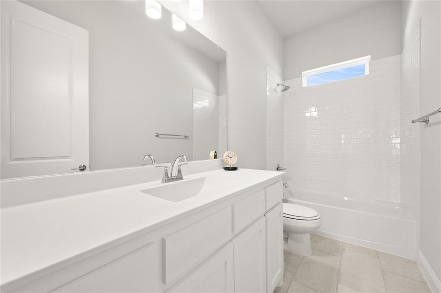 Full bathroom with tile patterned floors, tiled shower / bath combo, vanity, and toilet