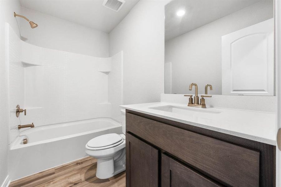 Full bathroom with vanity, toilet,  shower combination, and hardwood / wood-style flooring