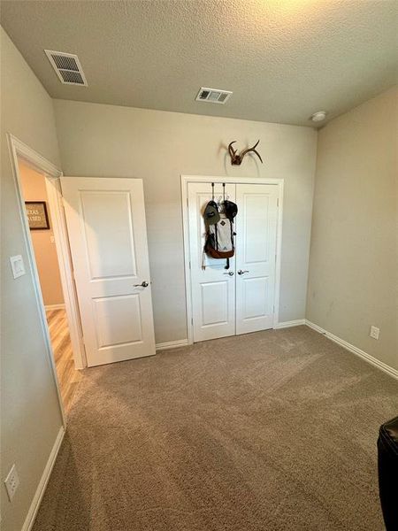 Unfurnished bedroom featuring a textured ceiling and carpet