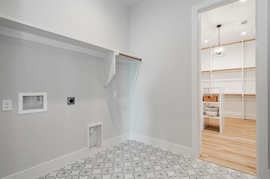 Example of builders Laundry room with hookup for an electric dryer, washer hookup, light wood-type flooring, and an inviting chandelier