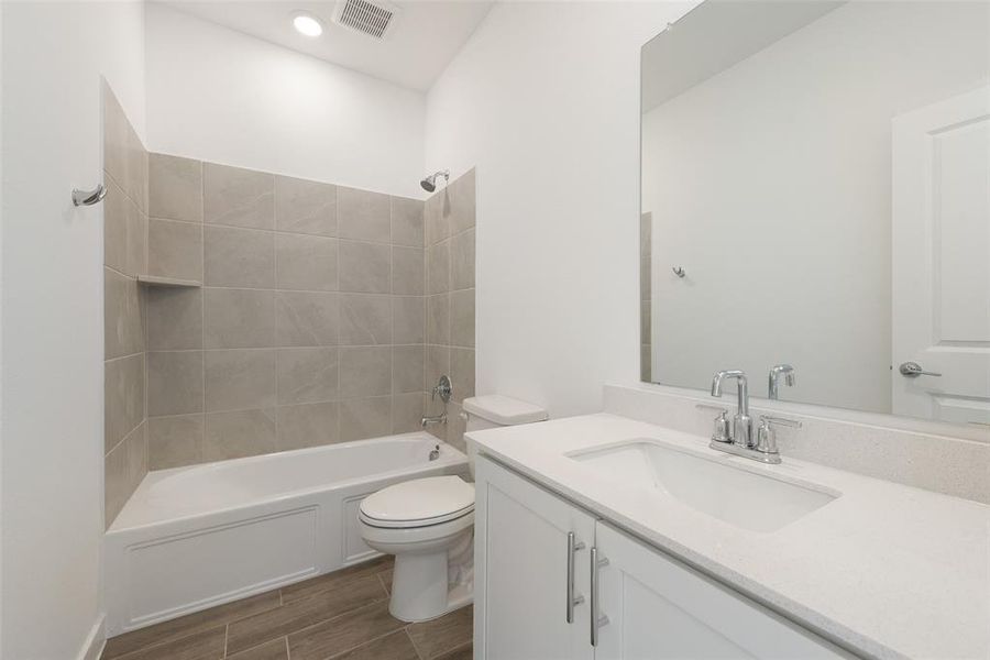 Full bathroom featuring vanity, tiled shower / bath combo, and toilet