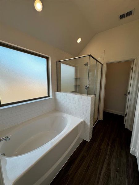 Bathroom featuring shower with separate bathtub, wood-type flooring, and lofted ceiling