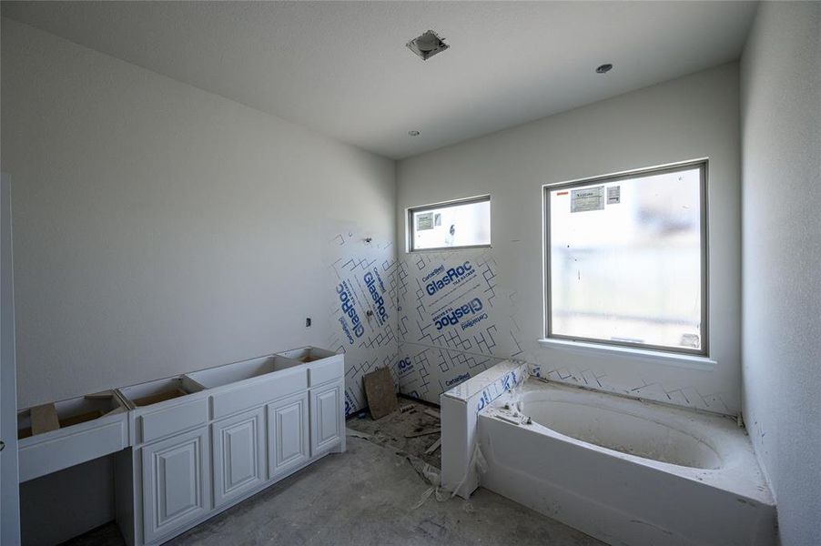 Bathroom with a tub and concrete flooring