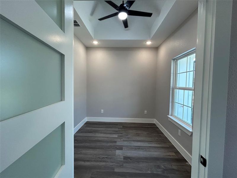 Unfurnished room featuring dark hardwood / wood-style floors, a tray ceiling, and ceiling fan