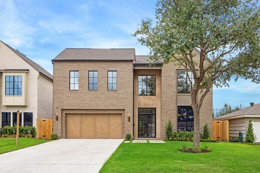 The front of the home during the day showcases its modern brick exterior with a large, two-car garage and professional landscaping, perfect for welcoming guests.