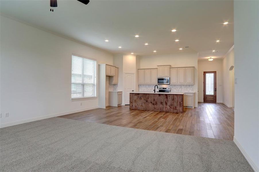 Kitchen with ceiling fan, light hardwood / wood-style flooring, a kitchen island with sink, and cream cabinets