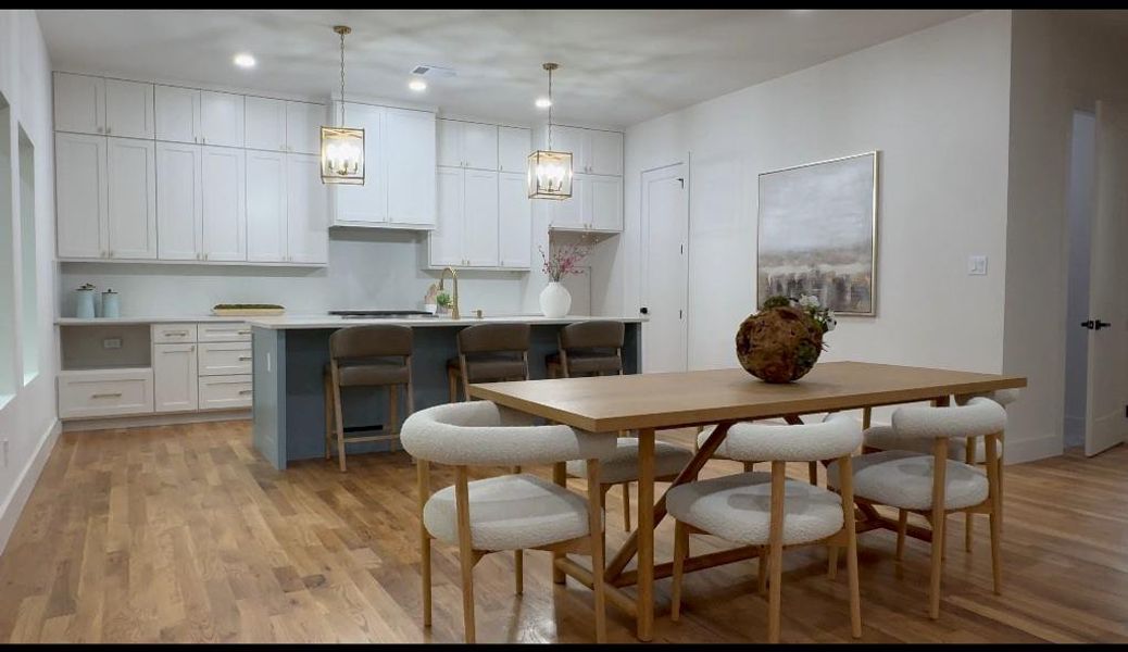 Kitchen with a kitchen bar, light hardwood / wood-style flooring, hanging light fixtures, a center island, and white cabinetry