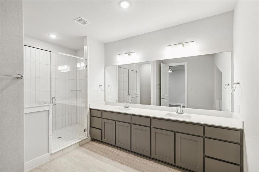 Bathroom with double sink vanity, an enclosed shower, and ceiling fan