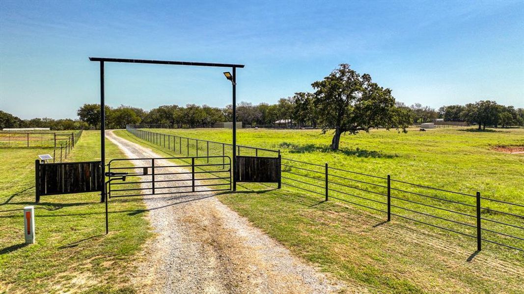 View of gate with a yard and a rural view