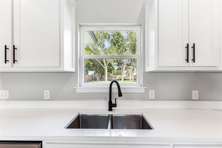 Kitchen featuring dishwasher, sink, and white cabinetry