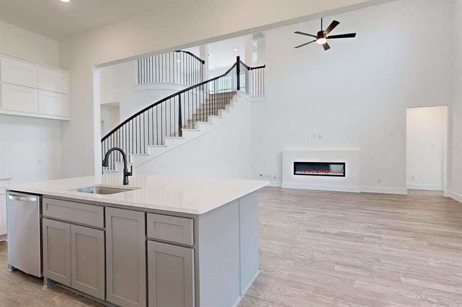 Kitchen featuring sink, a high ceiling, light wood-type flooring, dishwasher, and ceiling fan