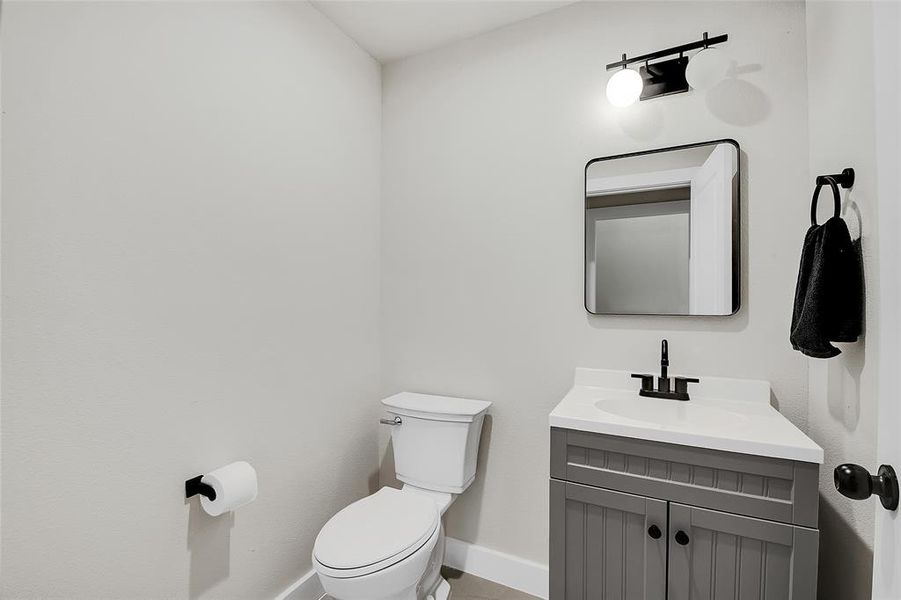 Downstairs Half Bathroom featuring vanity and toilet