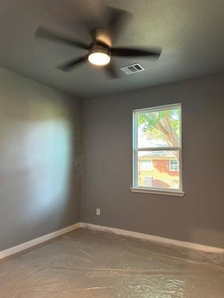 Empty room with ceiling fan and a textured ceiling