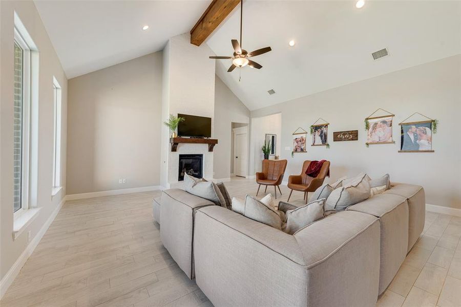 Living room with high vaulted ceiling, beamed ceiling, ceiling fan, and light hardwood / wood-style flooring