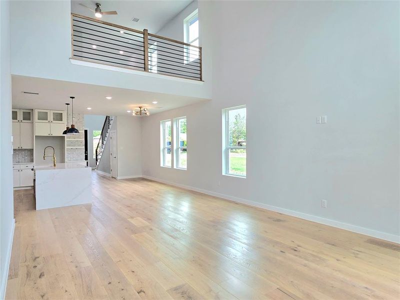 Unfurnished living room with sink, light hardwood / wood-style flooring, and a towering ceiling