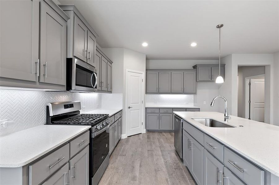 Kitchen with light hardwood / wood-style flooring, sink, pendant lighting, gray cabinetry, and stainless steel appliances