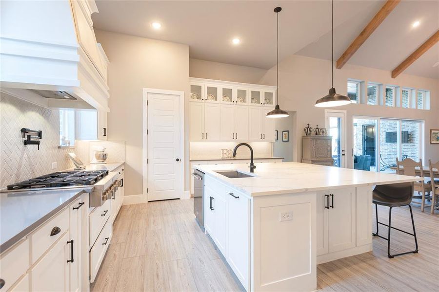 Kitchen with a center island with sink, sink, decorative backsplash, and white cabinetry