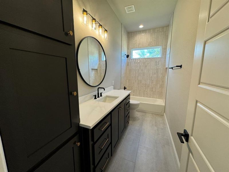 Full bathroom with vanity, tiled shower / bath combo, toilet, and tile patterned floors