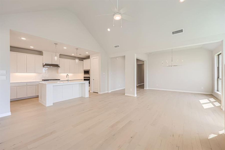 Kitchen featuring white cabinetry, light hardwood / wood-style floors, high vaulted ceiling, and stainless steel appliances