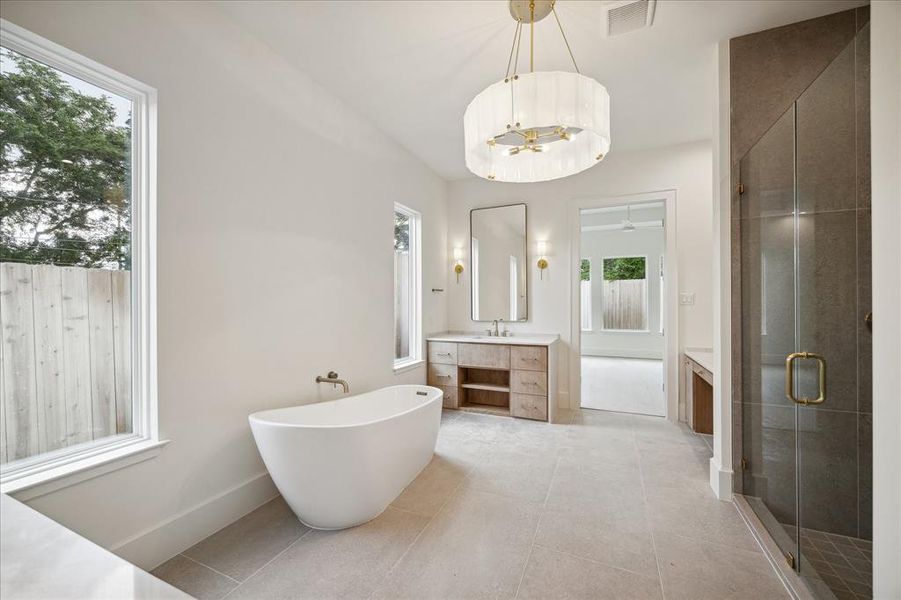 Every element of the primary bath has space to shine, giving an upscale, slightly European vibe. Exquisite sconce lighting and a well-scaled chandelier add modern elegance.