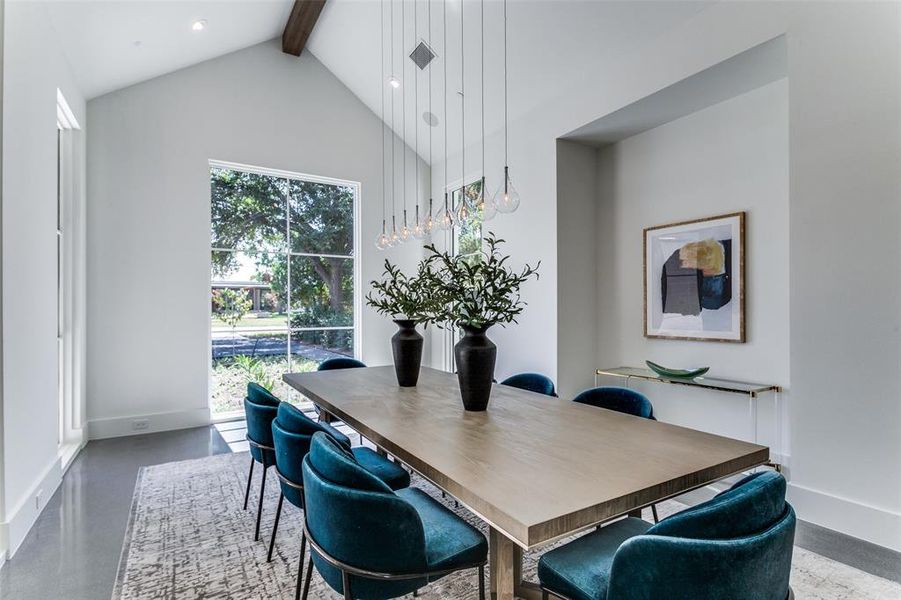 Dining room with beam ceiling, concrete floors, and high vaulted ceiling