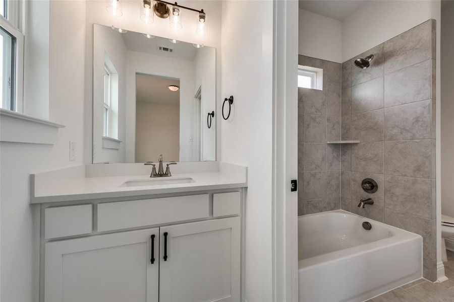 Full bathroom featuring tile floors, tiled shower / bath, toilet, and vanity