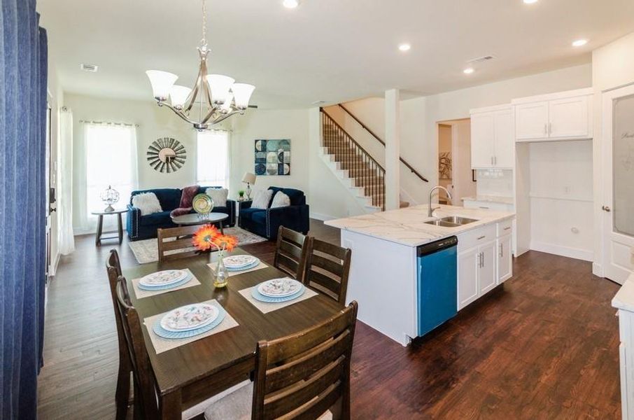 Kitchen featuring pendant lighting, light stone counters, sink, dark wood-type flooring, and stainless steel dishwasher