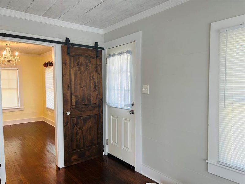 Entrance foyer featuring ornamental molding, a barn door, a notable chandelier, and dark hardwood / wood-style flooring