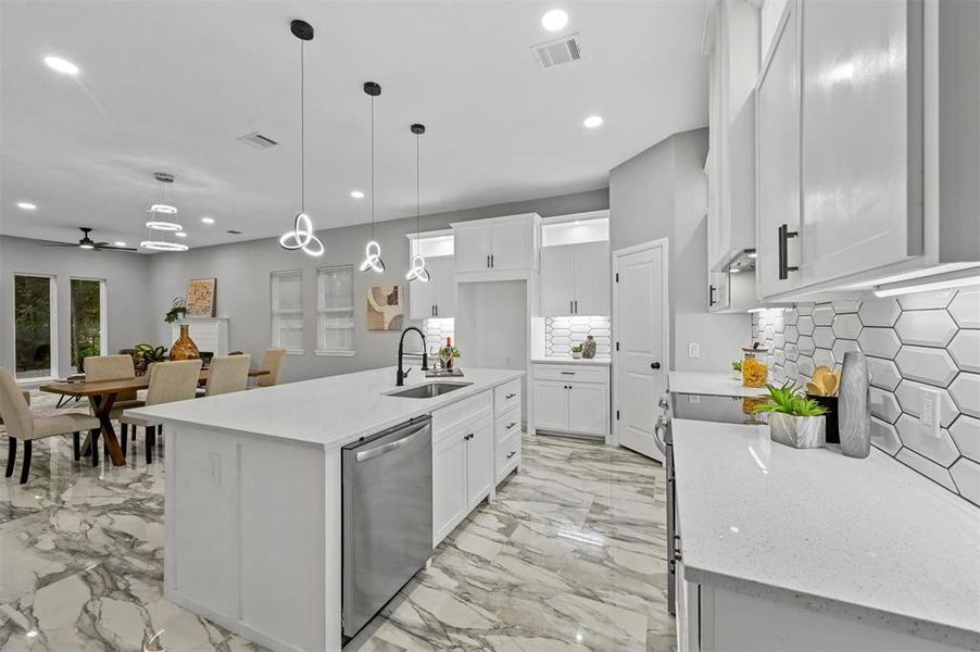 Kitchen with sink, stainless steel dishwasher, an island with sink