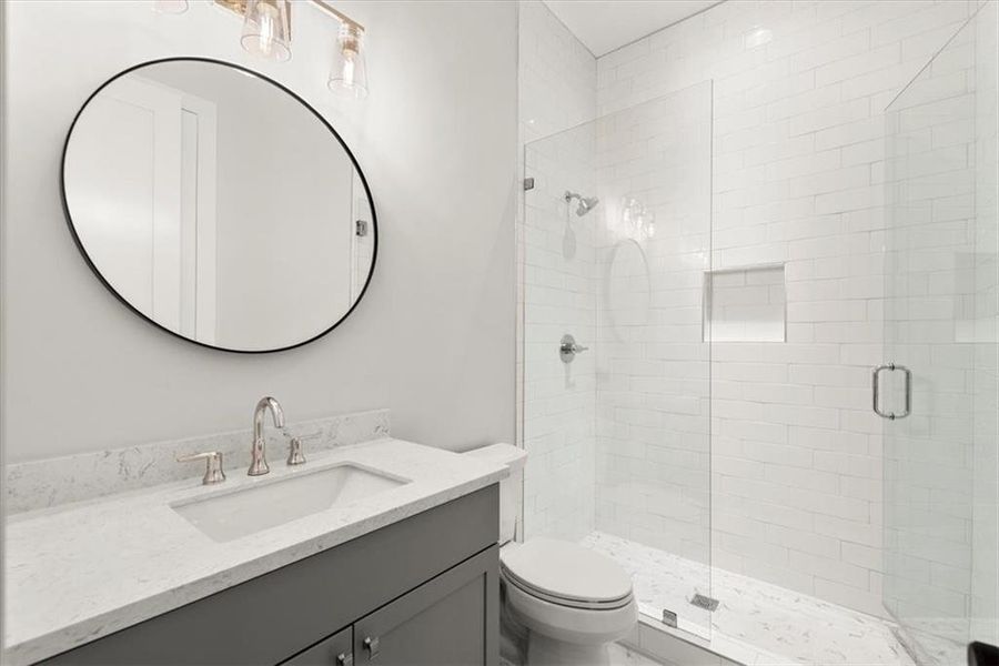 Bathroom with vanity, a shower with door, and toilet