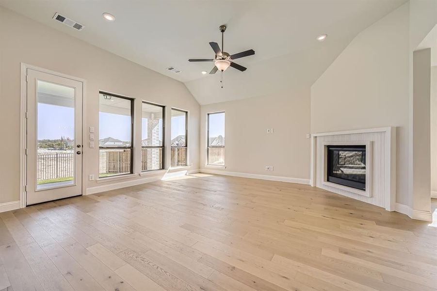 Unfurnished living room with lofted ceiling, light hardwood / wood-style floors, and a wealth of natural light