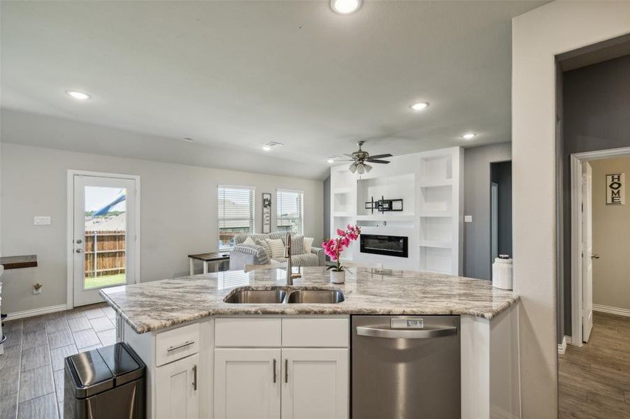 Kitchen featuring ceiling fan, light hardwood / wood-style flooring, stainless steel dishwasher, sink, and white cabinets