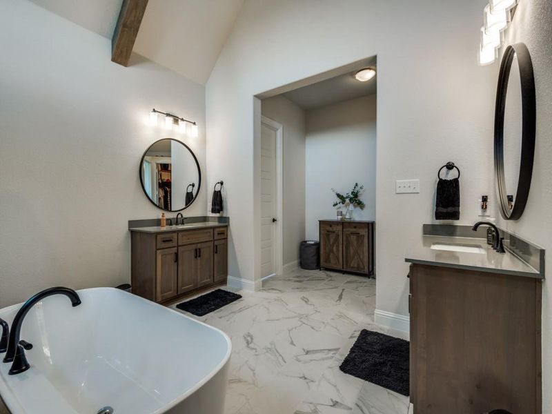 Bathroom with vanity, lofted ceiling with beams, and a bathing tub