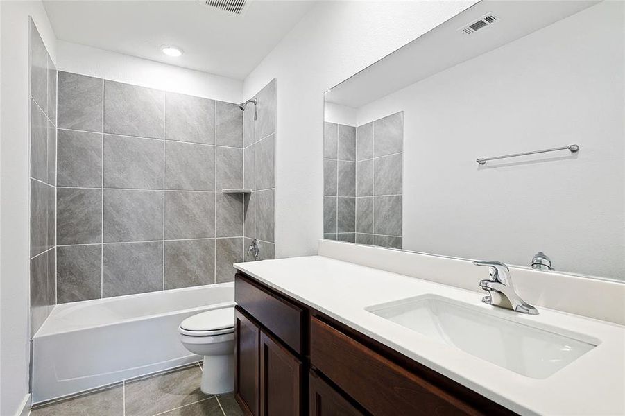 Full bathroom with vanity, tile patterned flooring, toilet, and tiled shower / bath